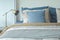 Blue and beige pillows on bed and chrome reading lamp