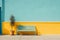 a blue bench against a yellow wall with a potted plant