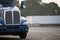 Blue big rig semi truck with chrome grill standing on wide parking lot with lines