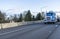 Blue big rig semi truck transporting fuel cargo in two tank semi trailer driving on the wide straight highway