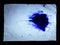 Blue blot ink on a sheet of white paper the black background