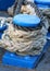 Blue boat mooring post covered with securing ropes.