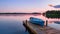 A blue boat resting on a wooden dock under clear blue skies, Small boat dock and a beautiful sunset landscape view with a huge