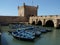 Blue boats next to an old tower in the fishing port of Essaouira, Morocco