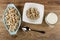 Blue bowl with corn rings, few corn rings in bowl, pitcher with yogurt, spoon on table. Top view