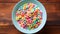 Blue bowl with fruit cereal rings with milk on a wooden background, top view banner