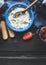 Blue bowl with mascarpone cream and wooden cooking spoon on dark wooden background, top view.