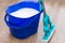 The blue bucket of the janitor cleaner is on the floor filled with water and detergent. Mop with a hand wringer is standing next