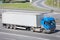 Blue cabin semitrailer with grey container driving on highway