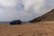 Blue camper van parked on a rocky beach on the wild coast of Andalusia
