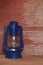 A blue camping lantern on red barn board