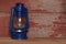 A blue camping lantern on red barn board