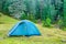 Blue camping tent in a green forest