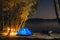 Blue Camping Tent Illuminated Inside. Night Hours Campsite. Recreation. Motorcycle traveler, tourist bikers. lake and stars. take