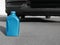 Blue canister with motor oil near car on asphalt road