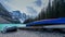 A blue canoe and silver boat parking on the shore at Moraine lake , Banff national park