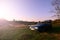 A blue car on a background of a rustic landscape with a wild cane field and a small lake. The family came to rest on the nature n