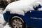 Blue car bumper covered with thick snow layer. Cold cyclone. Transport difficulties during snowy weather