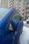 The blue car is covered with a thick crust of ice, freezing rain, in the city. Vertical photo.