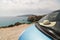 Blue car parked on sandy coast next to colourful rocks of Firiplaka beach on Milos island, Greece