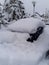 Blue car under a pile of snow parked in street in snowbank after blizzard