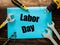 Blue card lying on the wooden boards between the assembly tools with the inscription `Labor Day` Concept of the holiday of working