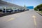 Blue carts on wheels for shopping in supermarket and cars parked under white shed on parking lot near hypermarket