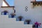 Blue ceramic garden pots with flowering plants on the stepped wall next to a villa staircase