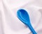 Blue ceramics spoon on white fabric background. Colorful concept