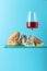 Blue cheese with bread, pink wine and rosemary on a blue background