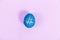 Blue chicken egg with a hashtag drawn on it on a purple background