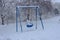 Blue childrens swing for the disabled in a snowy playground