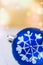 Blue Christmas ball with white snow flake ornament golden background with colorful confetti flare lights, copy space