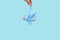 Blue Christmas gift with a blue ribbon in a woman`s hand hanging in the air, levitation on a blue background, for the text place.