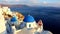 Blue church dome with wind playing with colorful flower shrub on a terrace of traditional cafeteria in typical greek