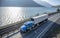 Blue classic American bonnet big rig semi truck trancporting cargo in refrigerated semi trailer moving on the road along the river