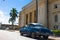 A blue classic car oldtimer parked in front of the government house