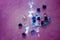 Blue and clear cut glass jewels on a pink painted background with a sprinkling of small rainbows of light