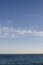 Blue clear water at mediteranean sea and clouds on sky and plane