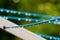 Blue clothing lines of a clothes spin with many raindrops at the string in front of a green background, after the rain. Retro way