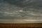 Blue clouds slowly float across the sky, over the newly plowed field, early spring morning