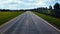 Blue clouds with sunlight hovers over rural roadway