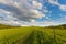 Blue cloudy sky over green hills and country road