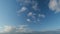 Blue cloudy sky with white clouds. Clear sky with few wispy stratocumulus clouds. Timelapse.