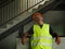 Blue collar job lifestyle. Portrait of young attractive and exhausted construction worker in helmet and vest at building site