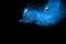 Blue color powder explosion cloud on black background.Closeup of Blue dust particles exhale on dark background