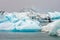 Blue colored melting icebergs floating around in Jokulsarlon glacier lagoon in Iceland during foggy weather.