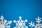 Blue colored paper background with white handmade snowflakes