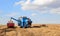 Blue combine in the field during harvest, peeling cereal grains and pouring with a pipe onto the trailer