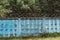 Blue concrete fence with barbed wires.